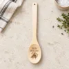 Shit Stirrer Engraved Wooden Spoon, on a limestone kitchen tabletop