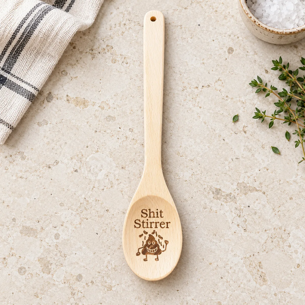 Shit Stirrer Engraved Wooden Spoon, on a limestone kitchen tabletop