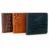 Dark brown, tan and black crocodile-pattern wallets standing together on a white background